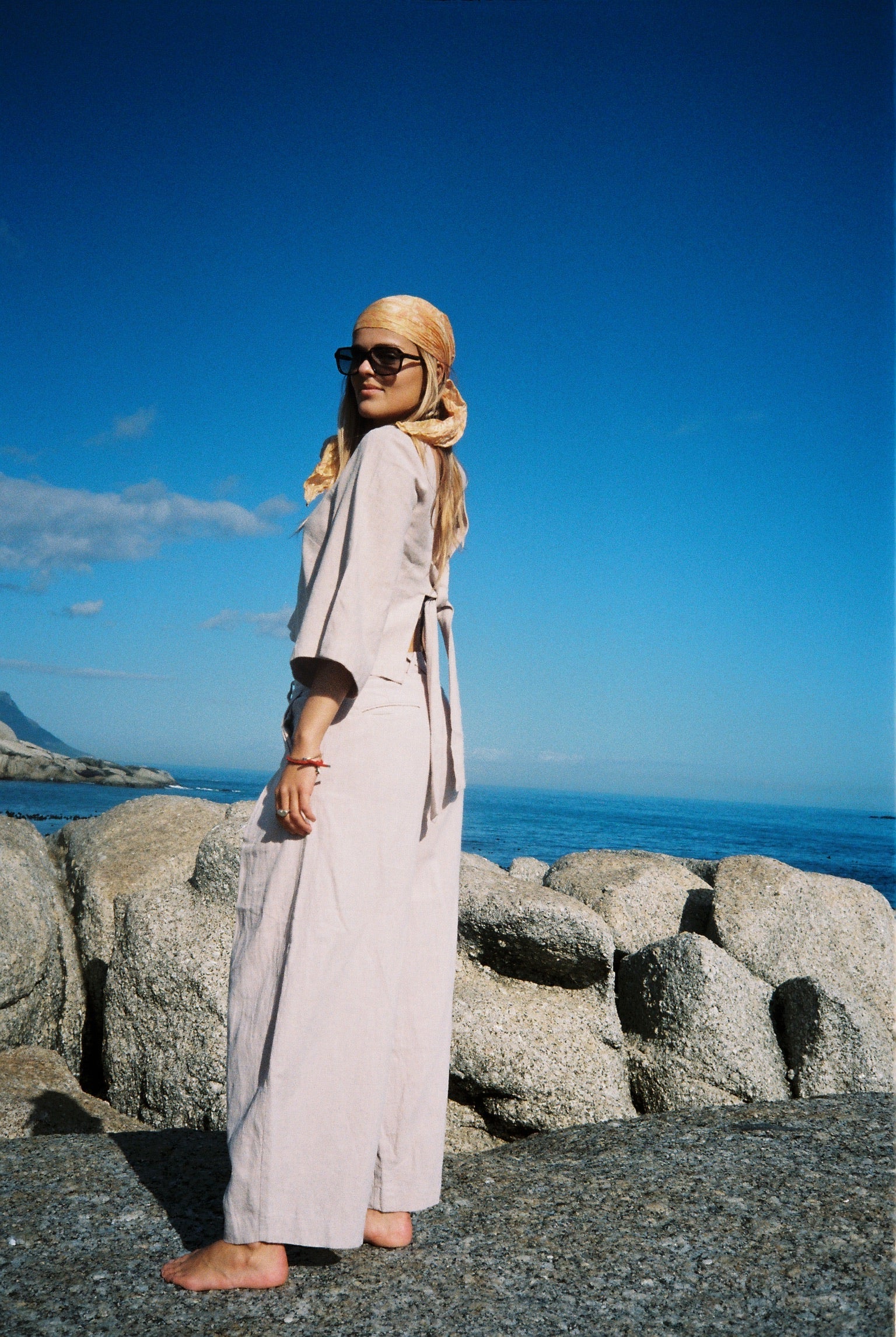Person standing against a blue wall with a stone structure